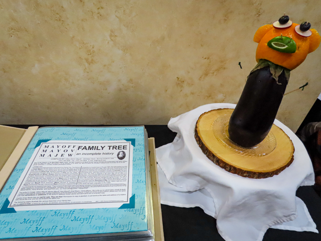 Page of the scrapbook featuring the family tree, guarded by sculpture of a vertical eggplant topped with an orange decorated like a face