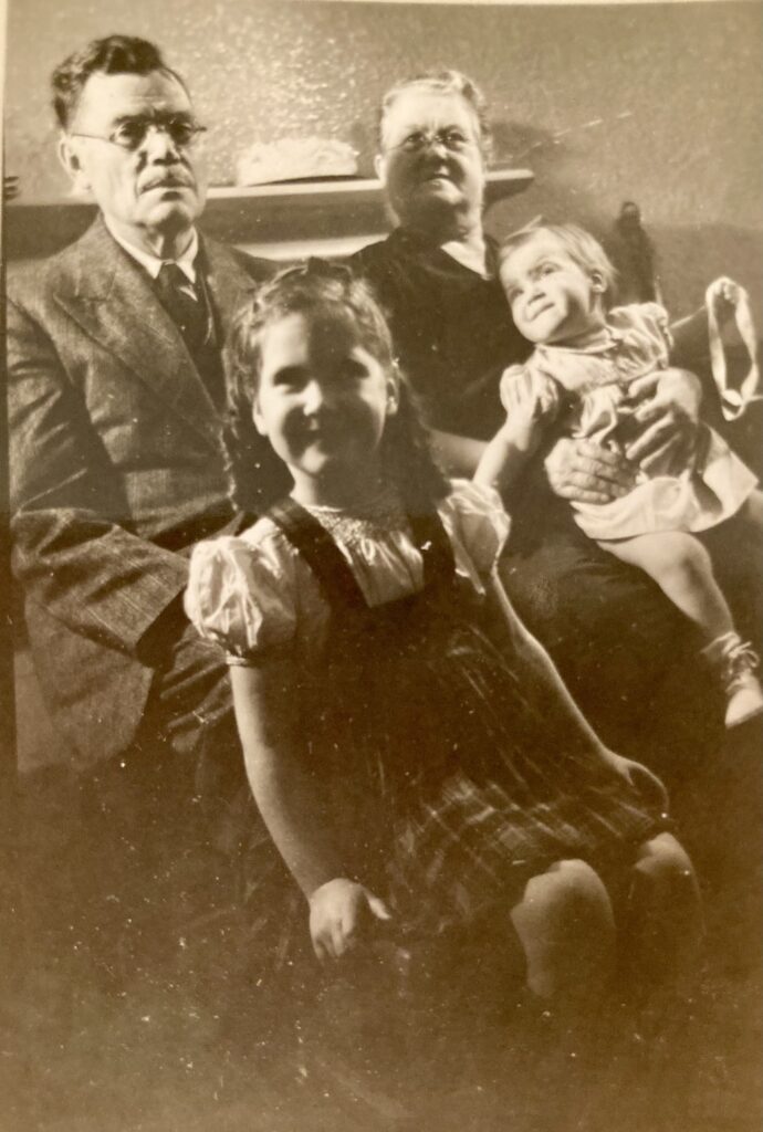 Sepia-toned photo of grandparents with two young granddaughters on their laps