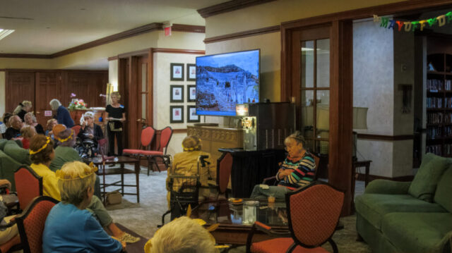 large group of seated people facing a large TV screen