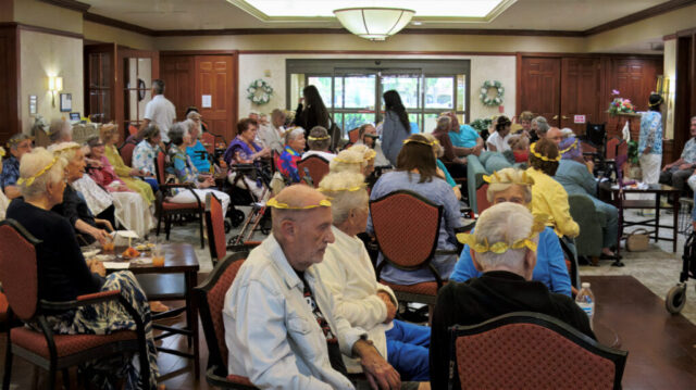 Large group of seated people wearing gold laurel leaf tiaras