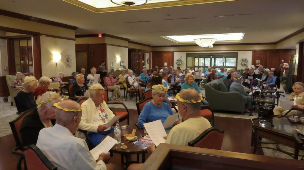 Large group of seated people wearing gold laurel leaf tiaras and holding song sheets