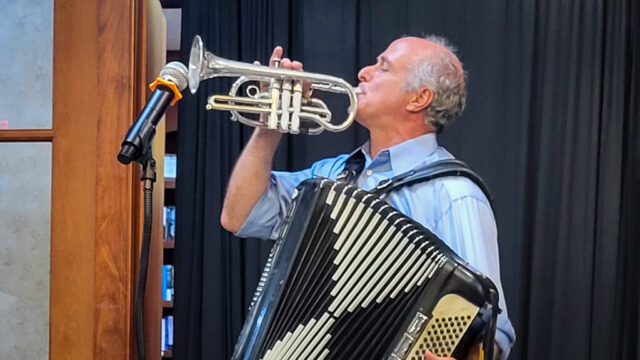 Oliver Steck blows his horn Man blowing cornet while holding accordion