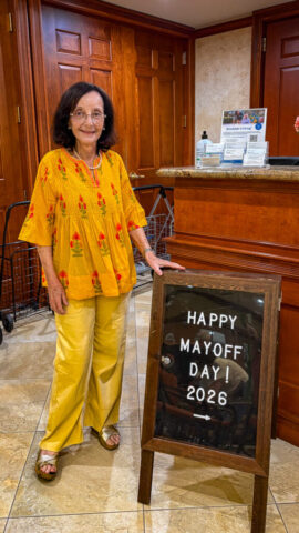 Laraine welcomed guests to the celebration Photo of woman standing next to Happy Mayoff Day! 2026 sign