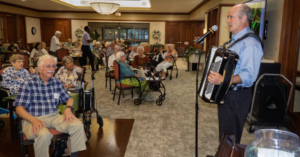 Photo of accordion player facing a smiling crowd that is singing along